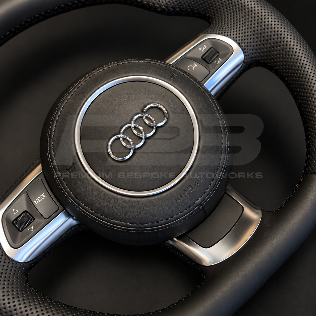 Audi R8 Gen 1 custom steering wheel, close view of the black smooth leather airbag cover with silver Audi rings, button trims and perforated grip