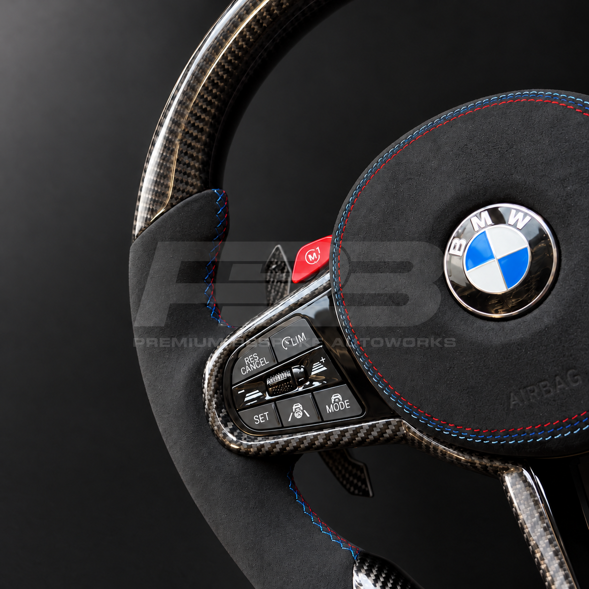 BMW M3 G80 LCI custom steering wheel close up detail showing flat bottom, gloss carbon fibre top, bottom and trims, black Alcantara grips and airbag cover with M tricolour stitching, red M buttons