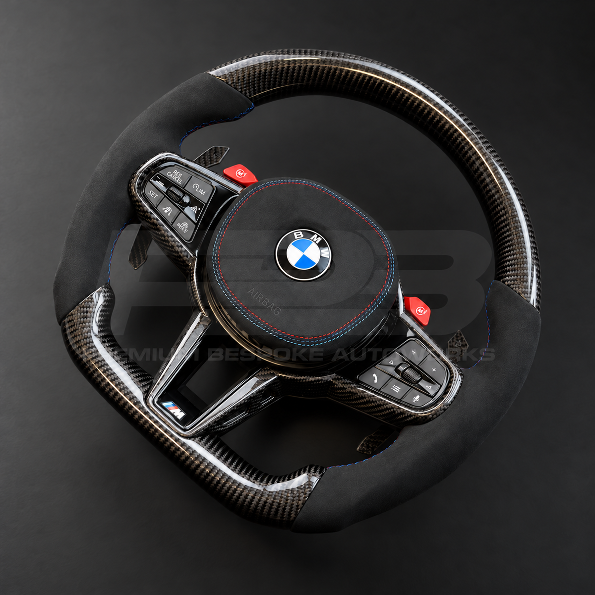 BMW M3 G80 LCI custom steering wheel right angle showing flat bottom, gloss carbon fibre top, bottom and trims, black Alcantara grips and airbag cover with M tricolour stitching, red M buttons