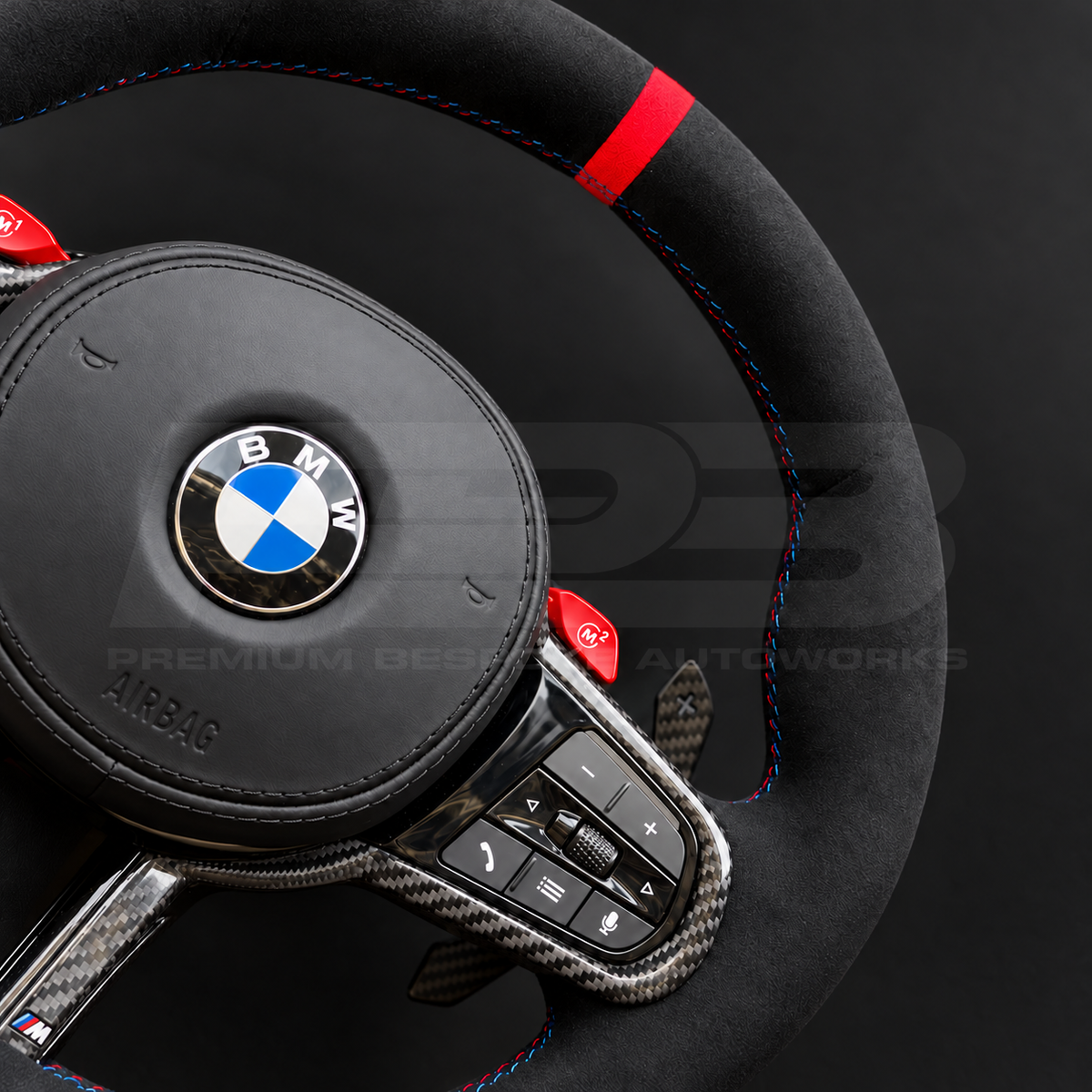 BMW M4 G82 LCI custom steering wheel close up detail showing full black Alcantara, red 12 o'clock marker, M tricolour stitching, Alcantara airbag cover, carbon trims, red M buttons