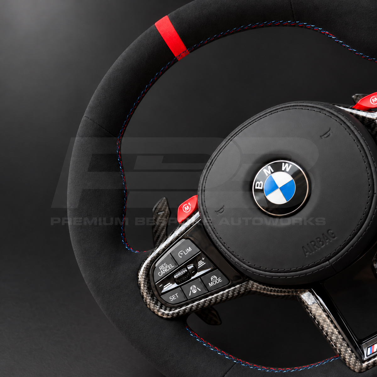 BMW M4 G82 LCI custom steering wheel close up detail showing full black Alcantara, red 12 o'clock marker, M tricolour stitching, Alcantara airbag cover, carbon trims, red M buttons