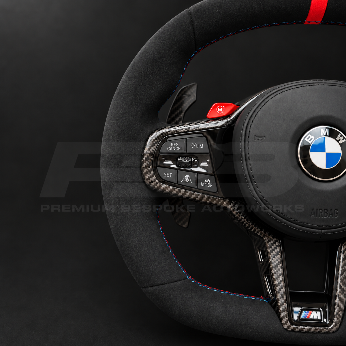 BMW M4 G82 LCI custom steering wheel close up detail showing full black Alcantara, red 12 o'clock marker, M tricolour stitching, Alcantara airbag cover, carbon trims, red M buttons