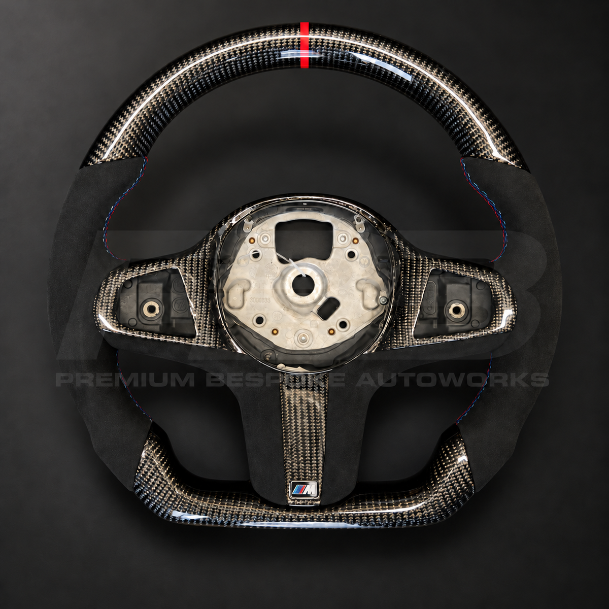 BMW X5 G05 custom steering wheel, front view, flat bottom gloss carbon fibre with red 12 o'clock strip, black Alcantara grips with M tricolour stitching and carbon spoke trims, customer build by Premium Bespoke AutoWorks