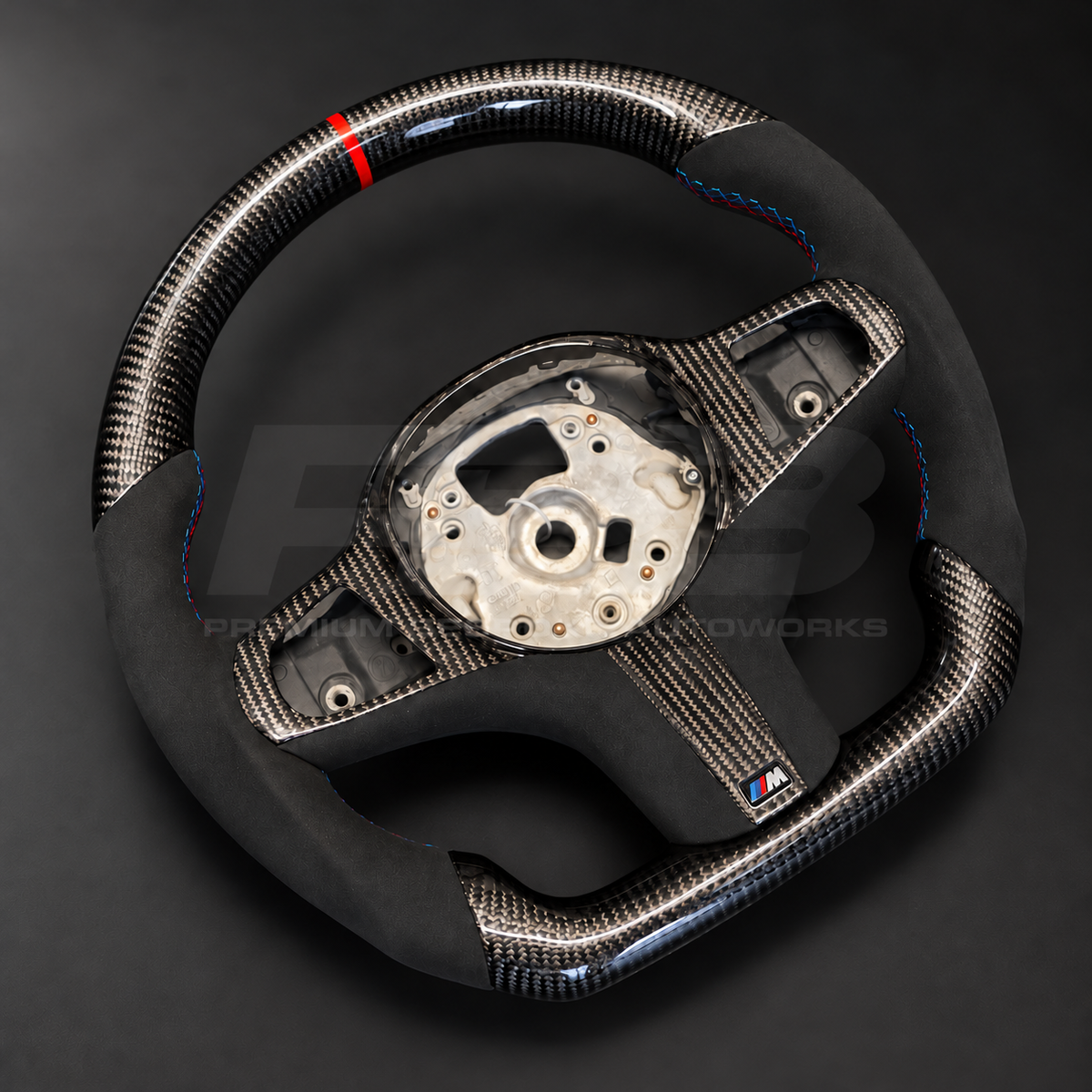 BMW X5 G05 custom steering wheel rotated to show the gloss carbon fibre top section with red strip and Alcantara grip