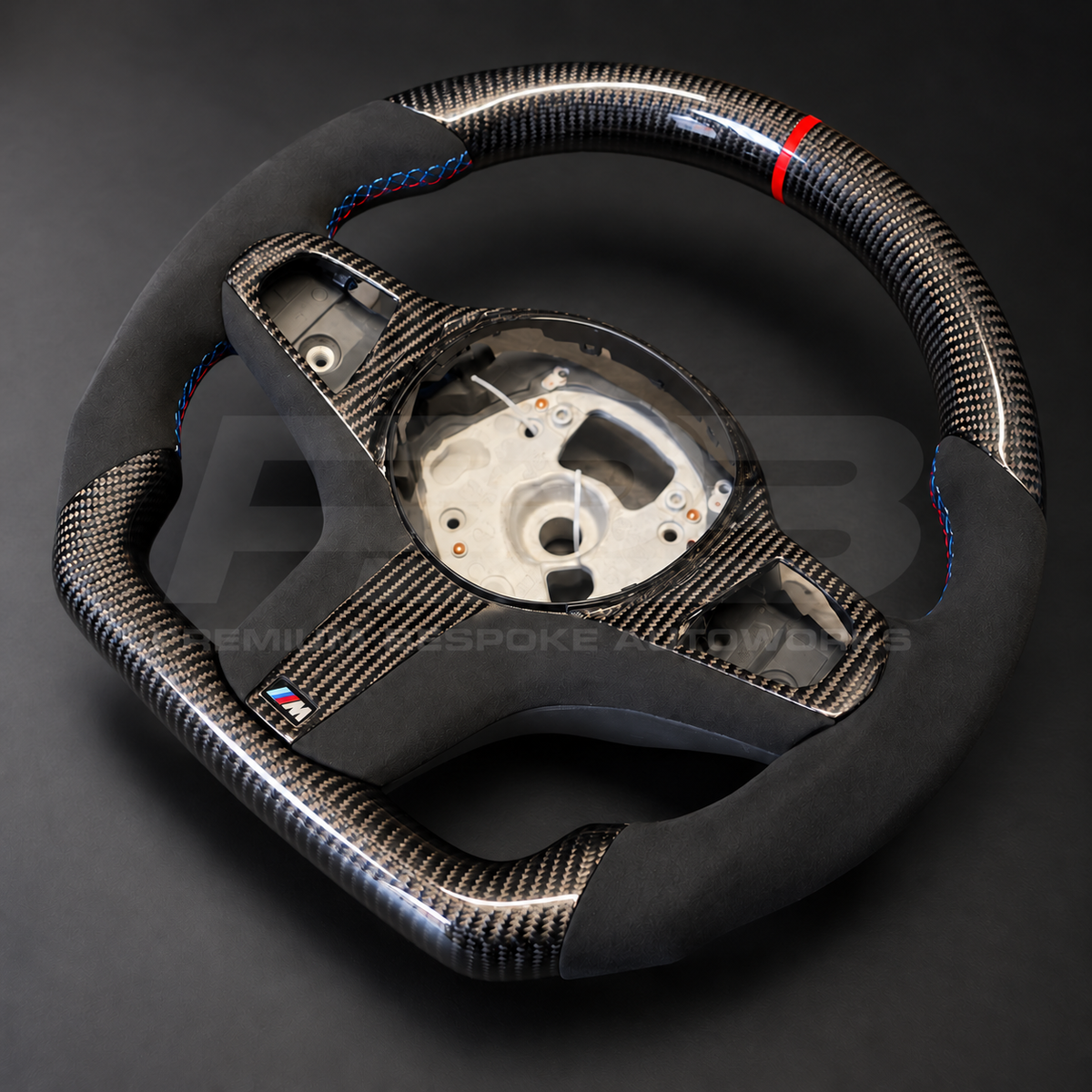 BMW X5 G05 custom steering wheel, side angle showing the carbon fibre top, Alcantara grip and carbon lower trim with M badge