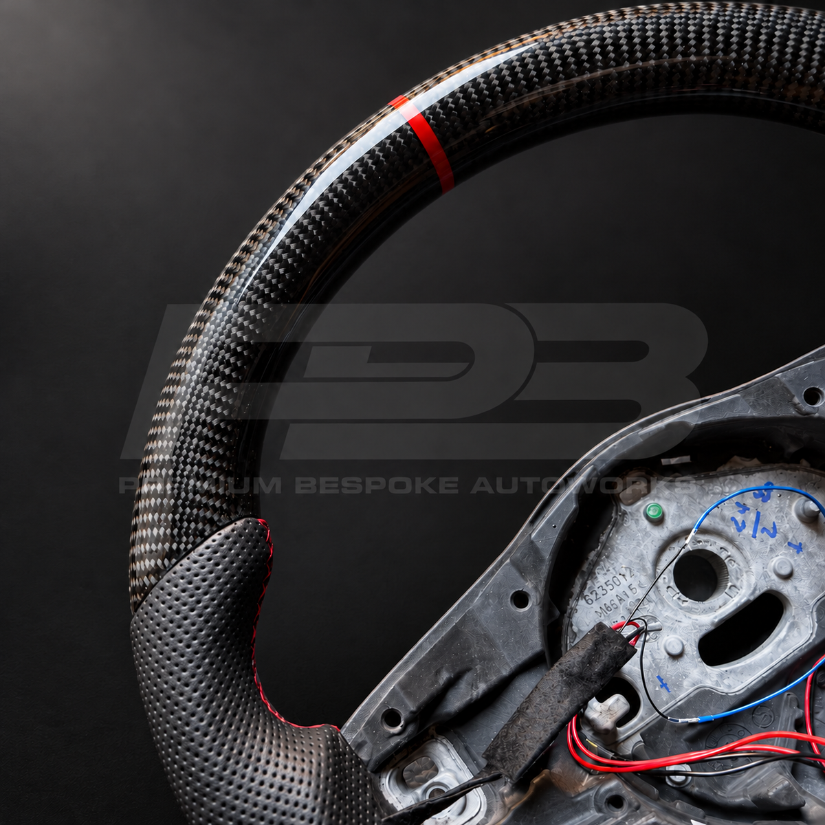 Close up of Jaguar F-Type custom steering wheel gloss carbon fibre weave, red 12 o'clock marker and perforated leather grip with red stitching