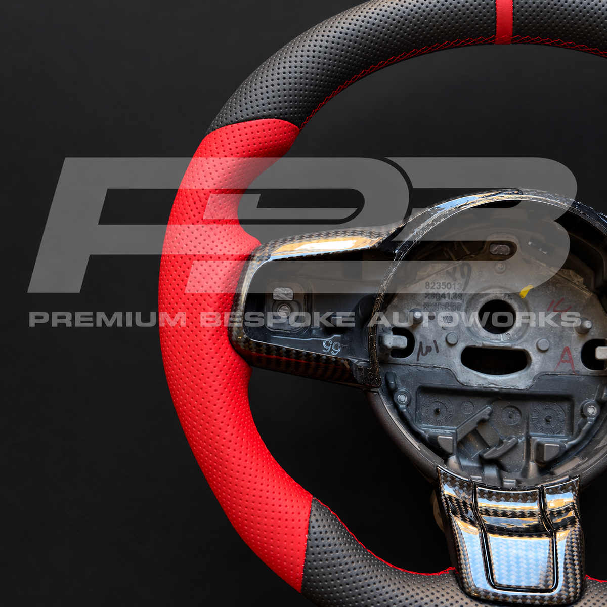 Close up of the carbon fibre spoke trims and red leather grip on a custom Jaguar F-Type steering wheel