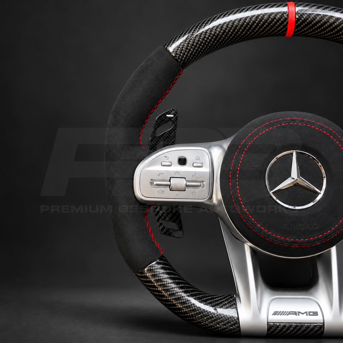 Mercedes-AMG A45 W177 custom steering wheel close up detail showing gloss carbon fibre, black Alcantara grips and airbag cover, red stitching and red marker