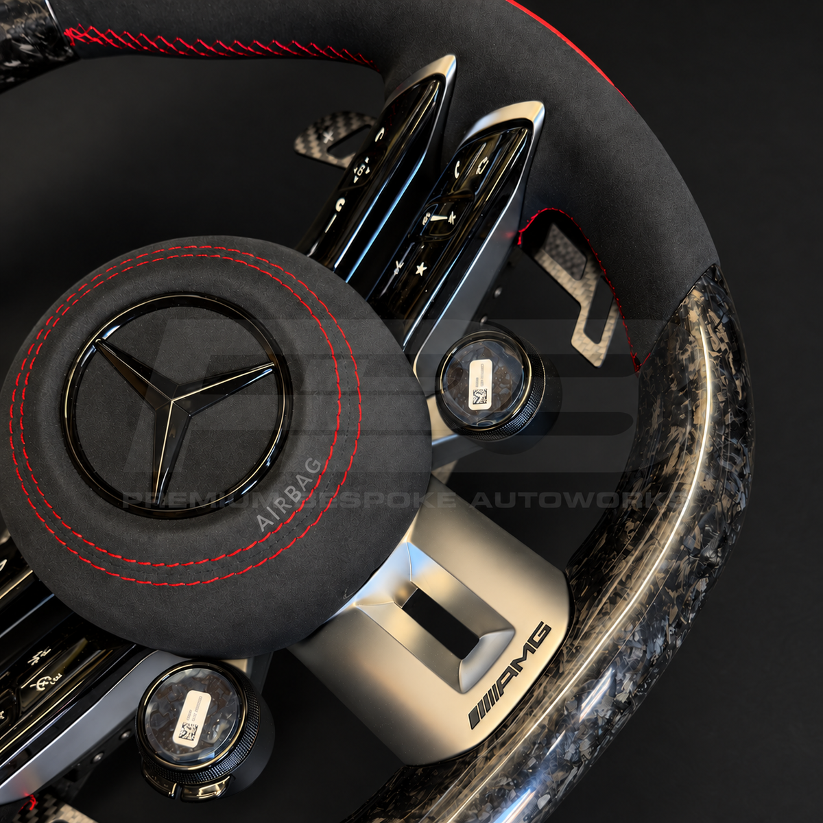 Mercedes-AMG CLA 45 S custom steering wheel, close view of the black Alcantara airbag cover with red stitching, forged carbon magnetic paddle and touch control pads