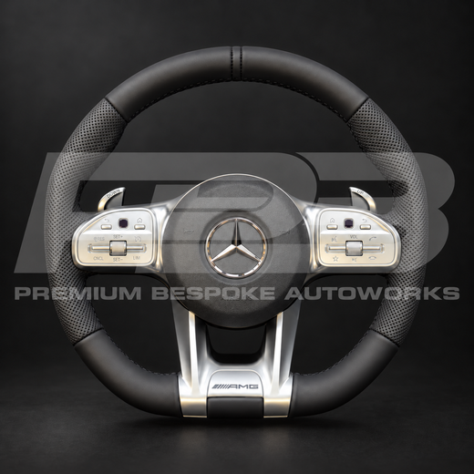 Mercedes-AMG G63 W463 custom steering wheel, front view: smooth black leather top and bottom, perforated black leather grips, black stitching, factory silver trims and paddle shifters, airbag fitted