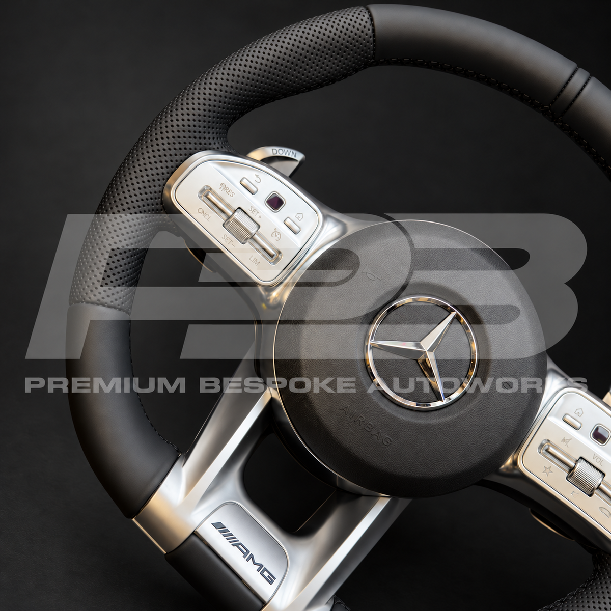 Mercedes-AMG G63 W463 custom steering wheel angled from the left, showing the perforated leather grip, smooth leather rim and silver AMG trim