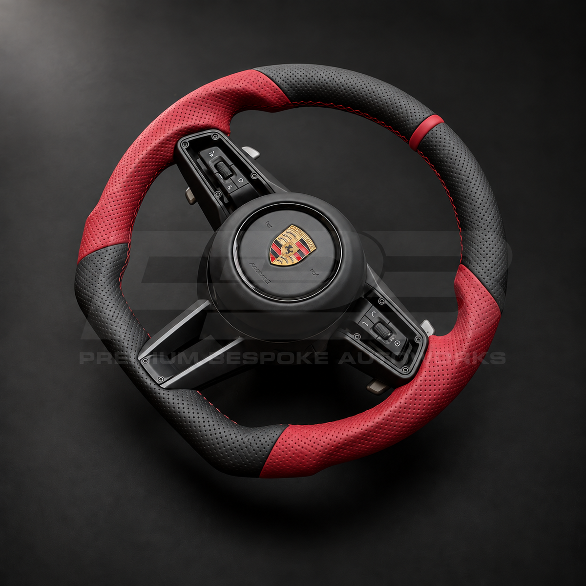 Porsche 911 992 custom steering wheel left angle showing flat bottom, perforated black leather, red perforated grips, red stitching and red 12 o'clock marker