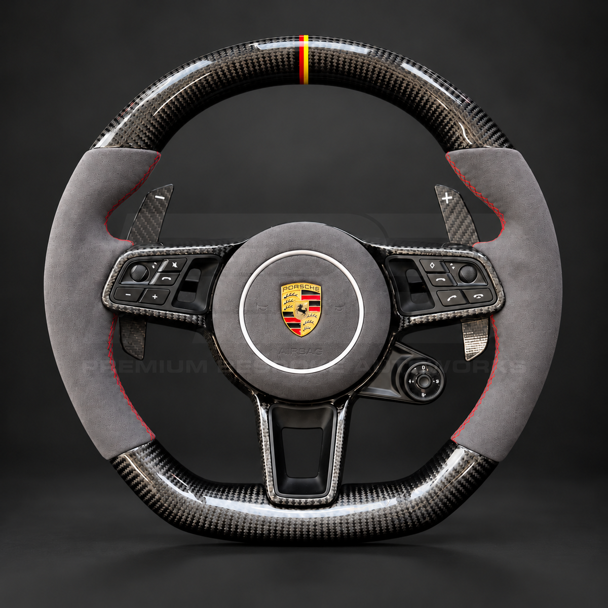 Porsche Cayenne 9Y0 custom steering wheel front view showing gloss carbon fibre, grey Alcantara grips and airbag cover, red stitching and German flag marker