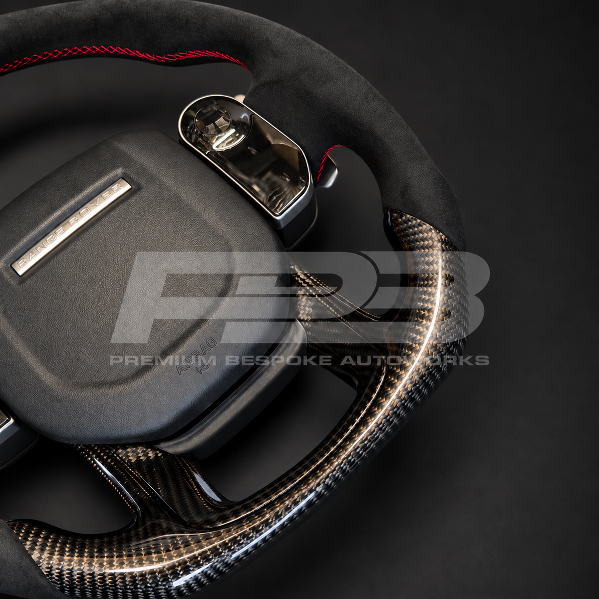 Close up of Range Rover Sport L494 custom steering wheel airbag, touch controls and red stitching on the Alcantara rim