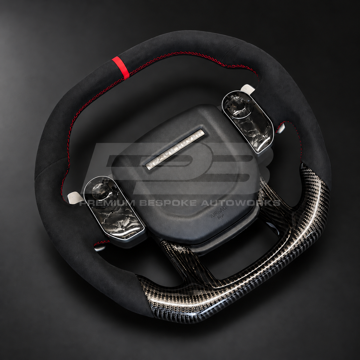 Range Rover Sport L494 custom steering wheel left angle showing red stitching on black Alcantara and the carbon fibre lower spoke trim