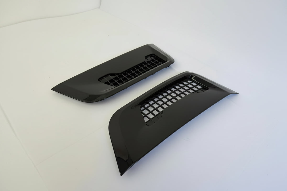 Two black plastic defender l663 side vent trims with on a white background