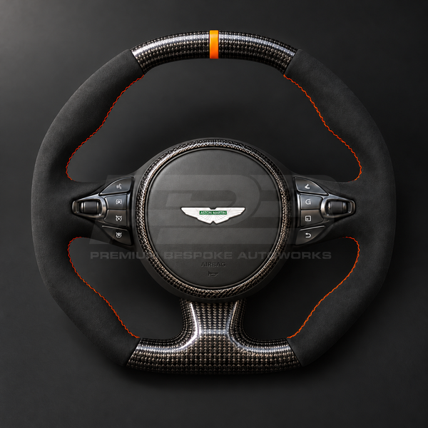 Aston Martin Vantage Facelift custom steering wheel front view showing flat top and bottom, gloss carbon fibre, black Alcantara grips, orange stitching and orange marker