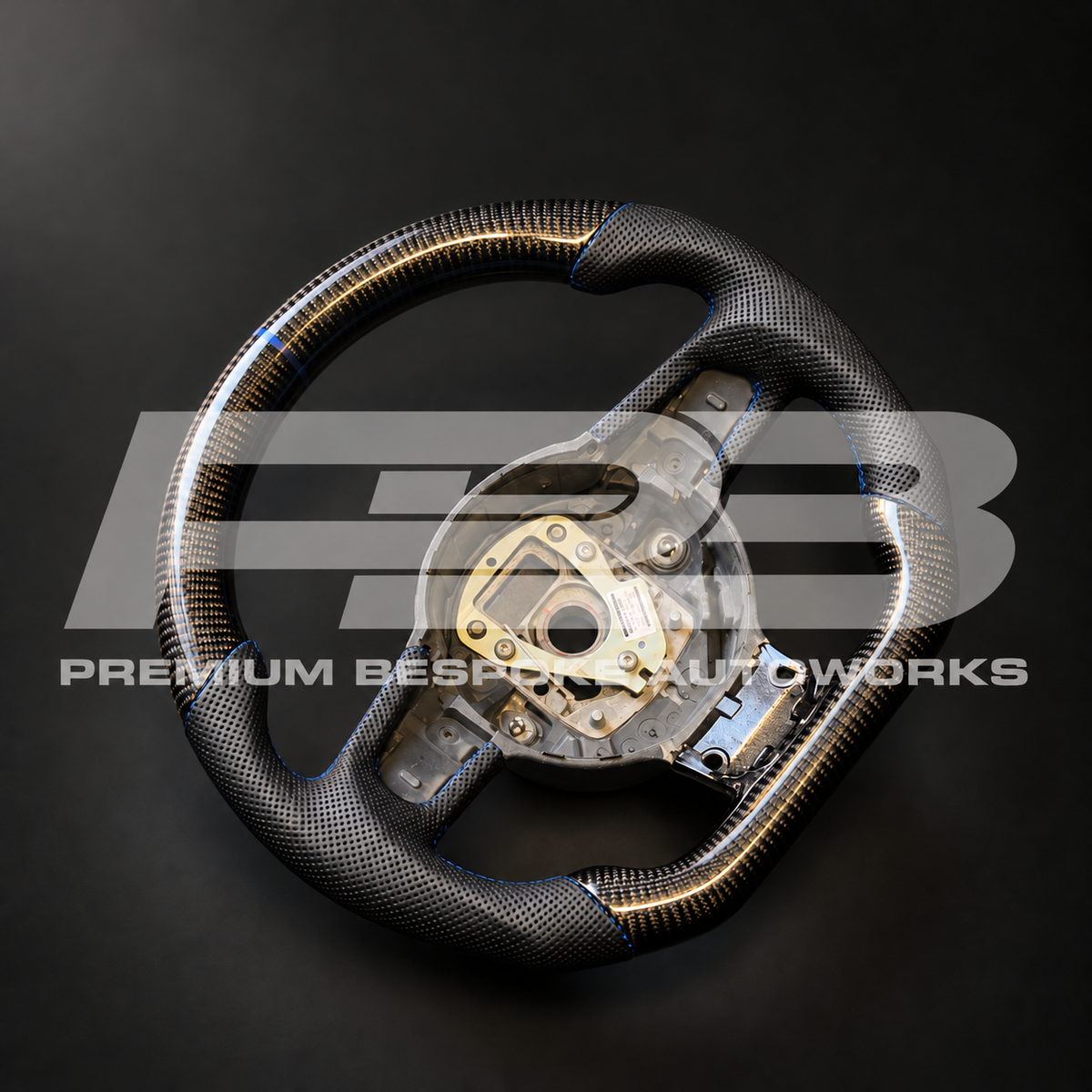 Audi R8 Gen 1 custom steering wheel angled from the left, gloss carbon fibre with perforated leather grips and navy blue stitching