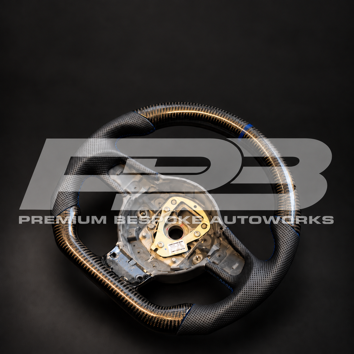 Audi R8 Gen 1 custom steering wheel angled from the right, showing the flat bottom carbon fibre section and navy blue stitched grips