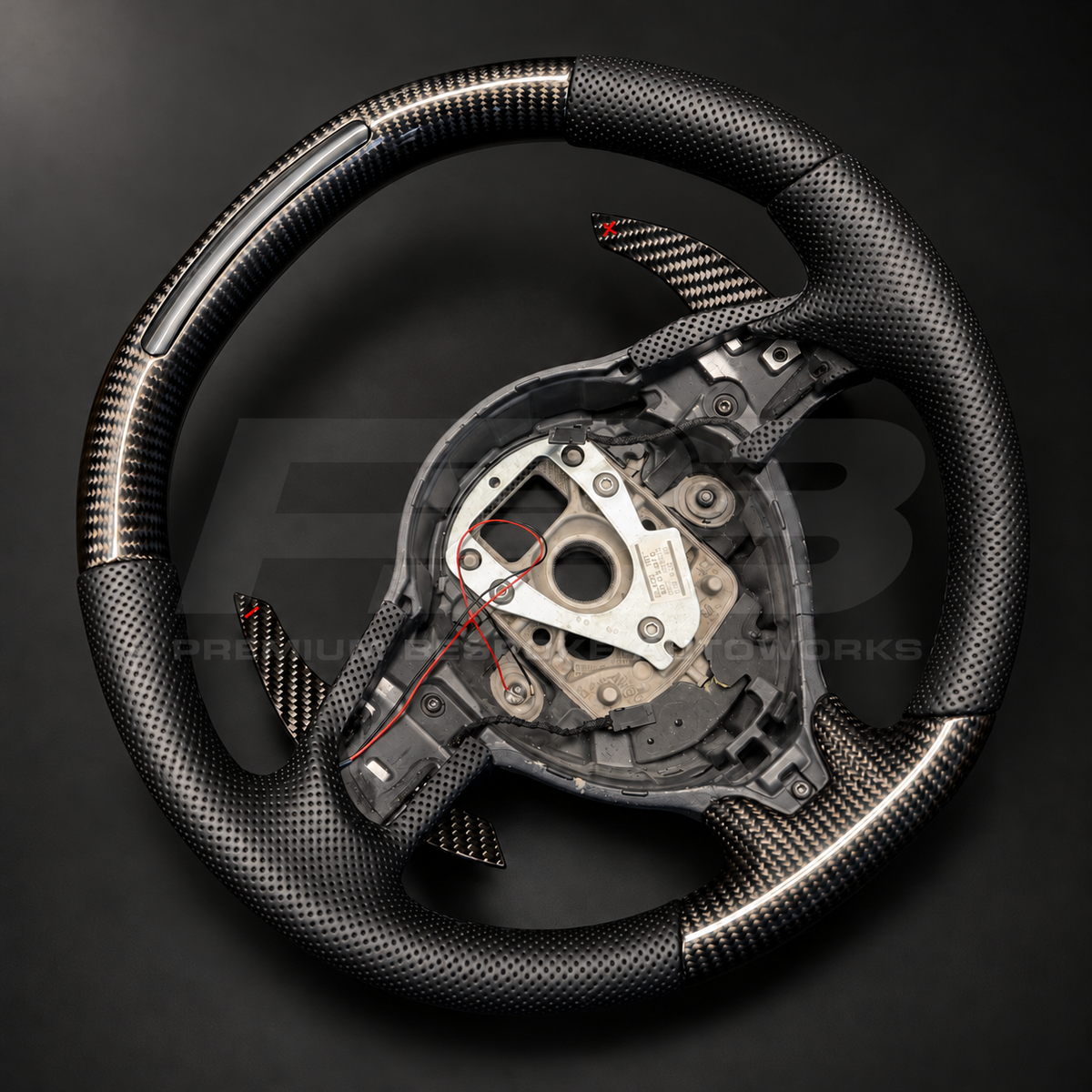 Audi R8 Gen 1 custom steering wheel, angled view showing the carbon fibre weave, perforated black leather grip and gloss carbon paddle shifters