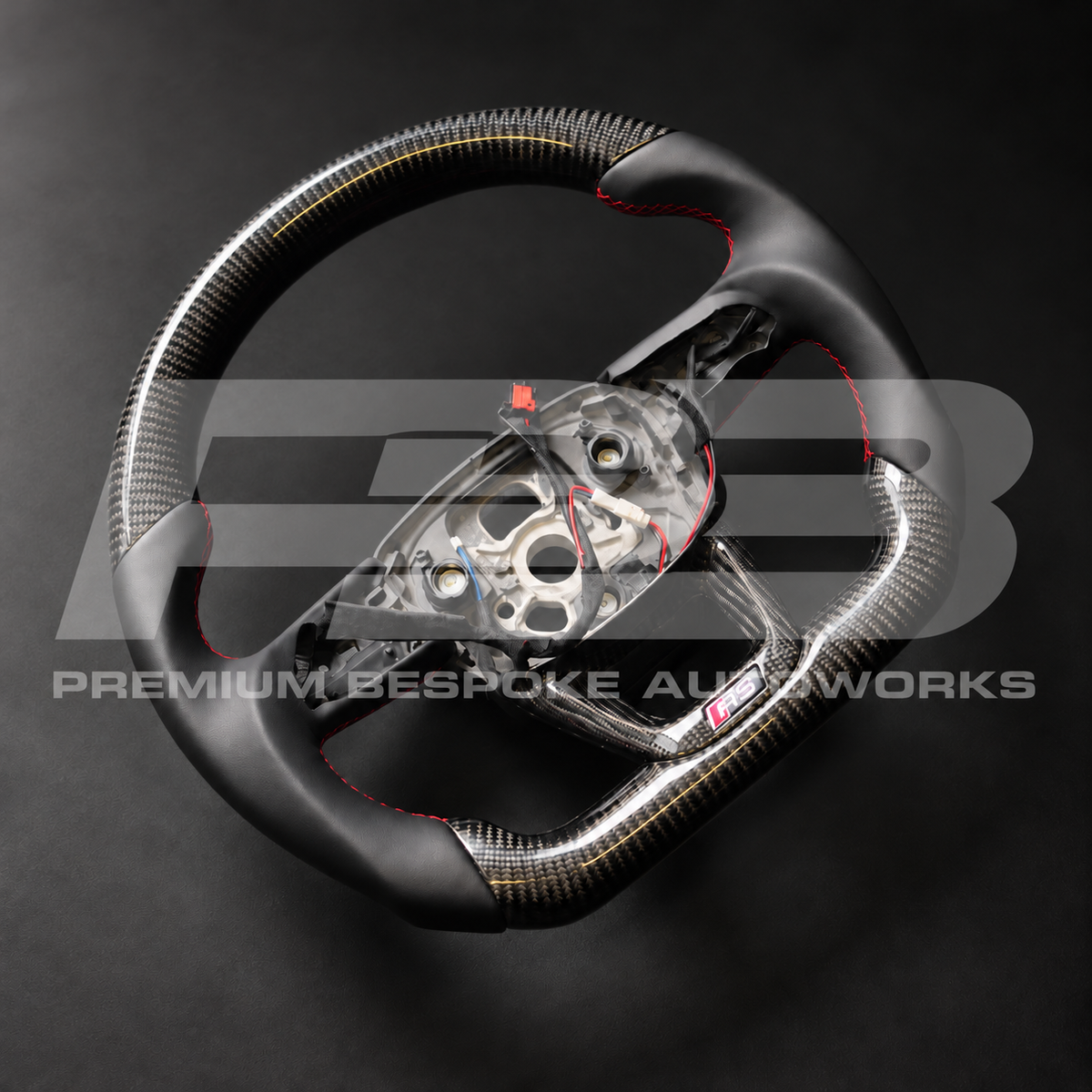 Audi RS Q8 custom steering wheel angled from the left, gloss carbon fibre with black leather grips and red stitching