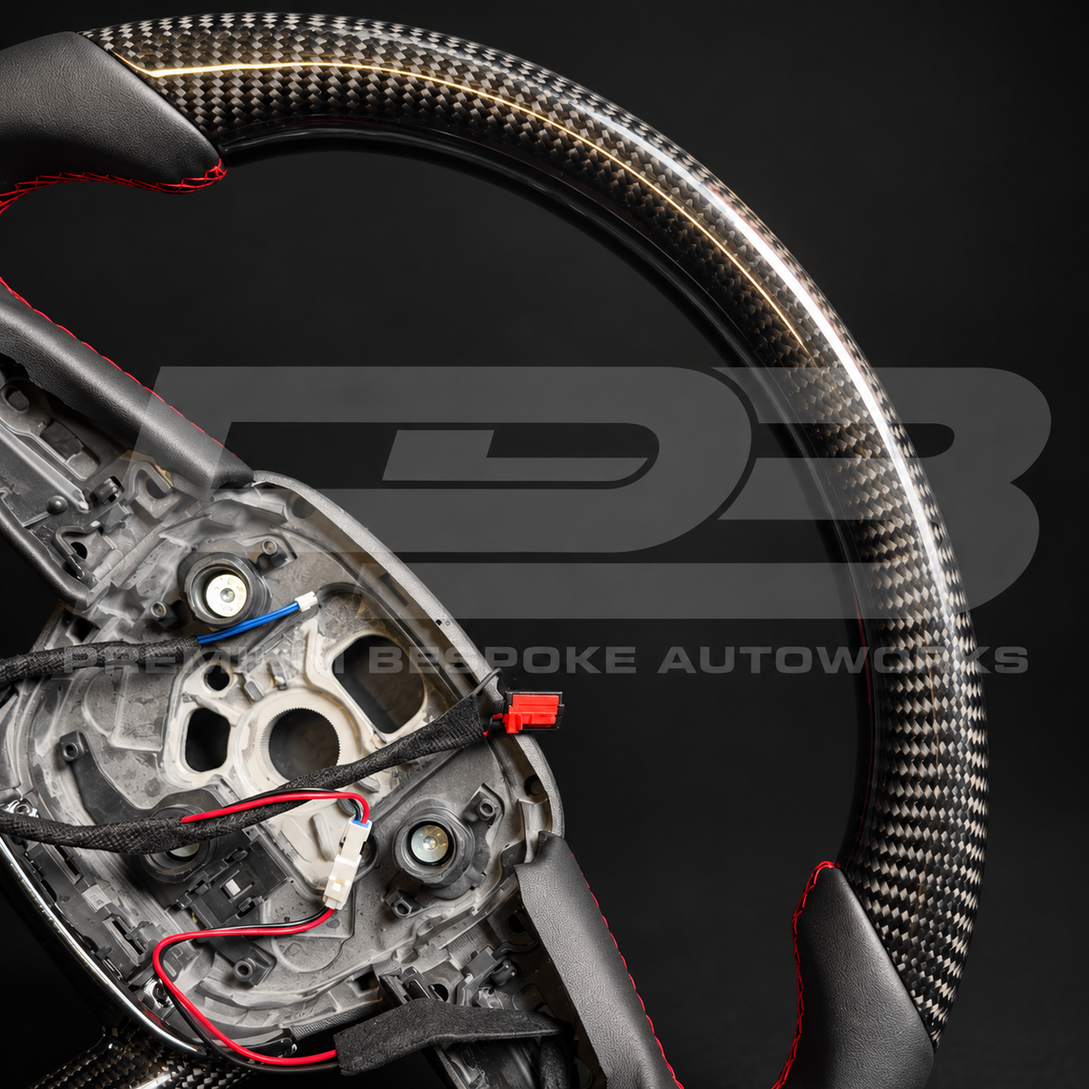 Close up of the gloss carbon fibre top section and red stitched leather grip on an Audi RS Q8 custom steering wheel