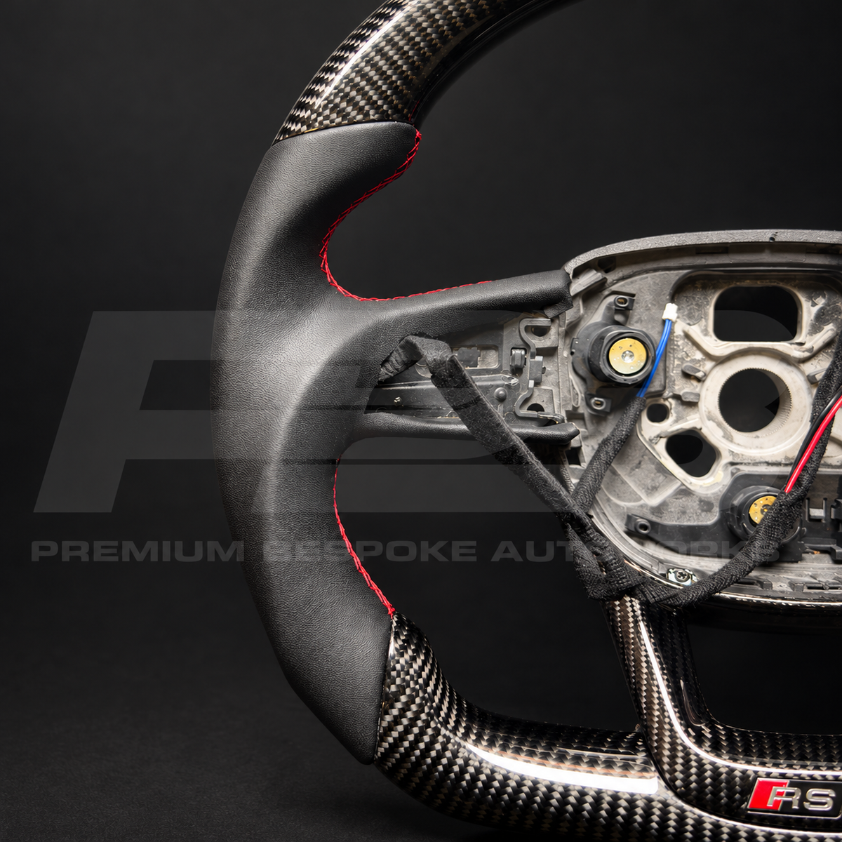 Audi RS Q8 custom steering wheel from above, gloss carbon fibre top section with black leather grips and red stitching