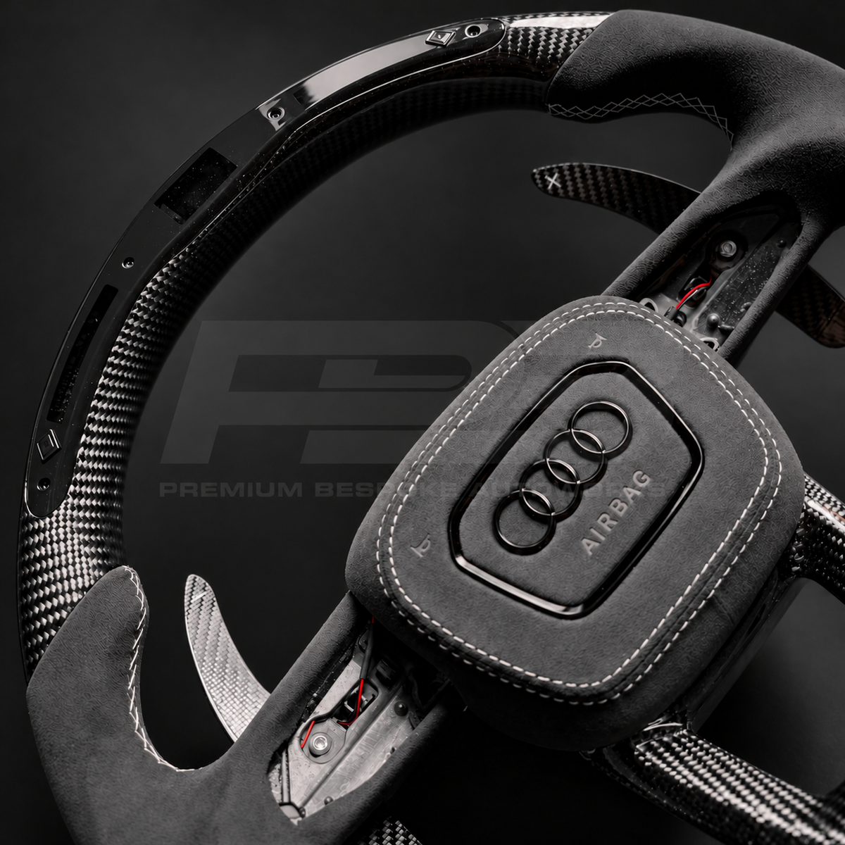Audi RSQ8 custom steering wheel close up detail showing flat top and bottom, gloss carbon fibre, RPM race display, grey Alcantara grips and airbag cover, carbon paddles
