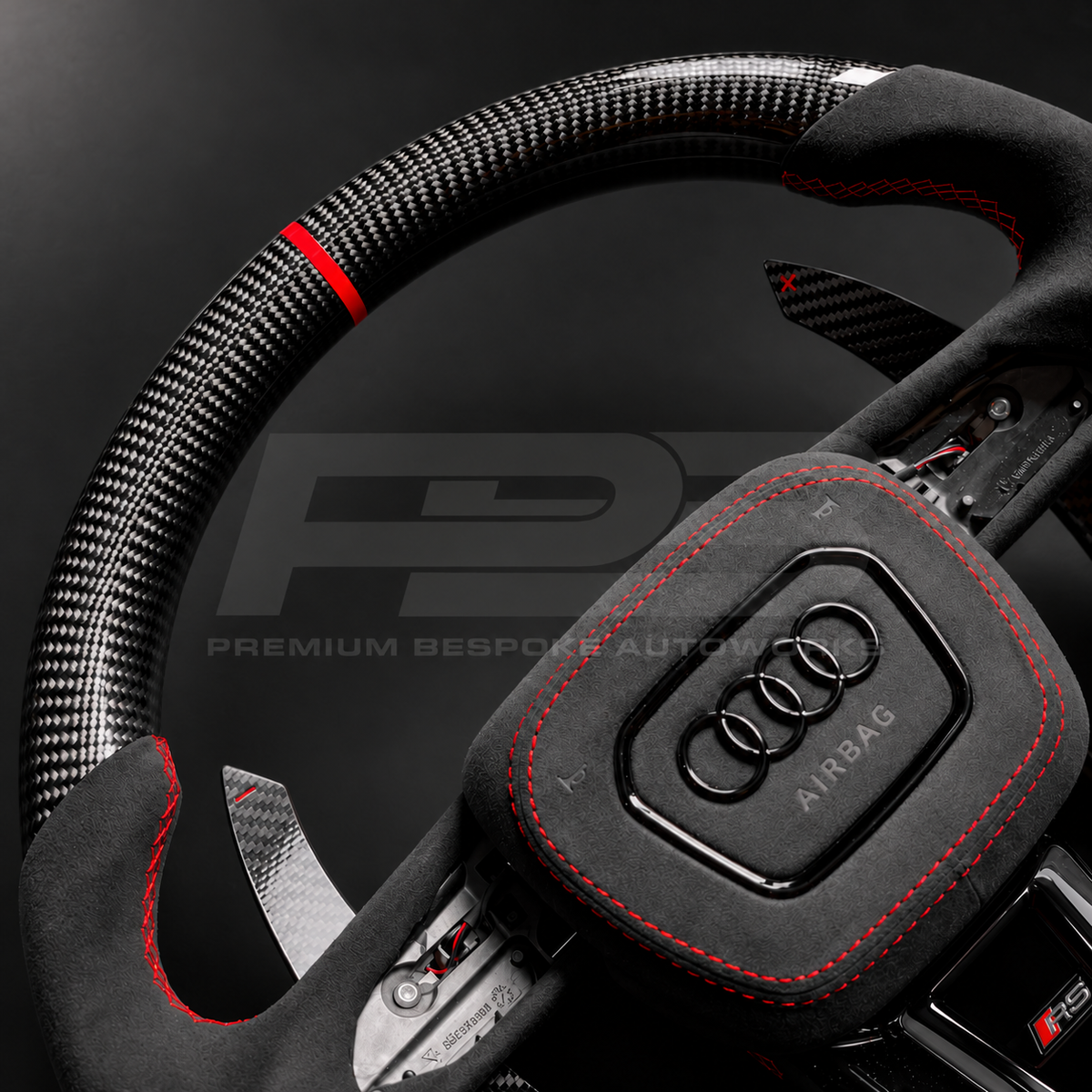 Audi RS3 8Y custom steering wheel close up detail showing flat bottom, gloss carbon fibre top and bottom, red marker, black Alcantara grips and airbag cover with red stitching