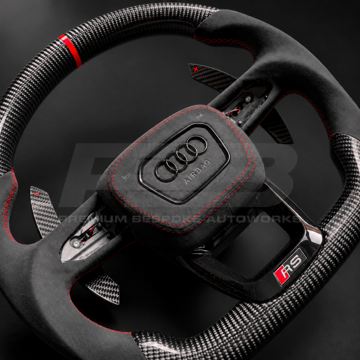 Audi RS3 8Y custom steering wheel close up detail showing flat bottom, gloss carbon fibre top and bottom, red marker, black Alcantara grips and airbag cover with red stitching