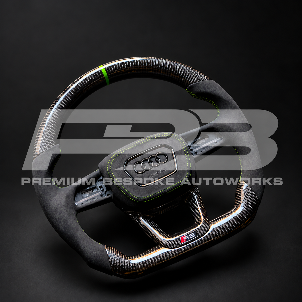 Audi RS3 8Y custom steering wheel angled from the right, showing the Alcantara airbag cover with green stitching and the carbon fibre lower trim with RS badge