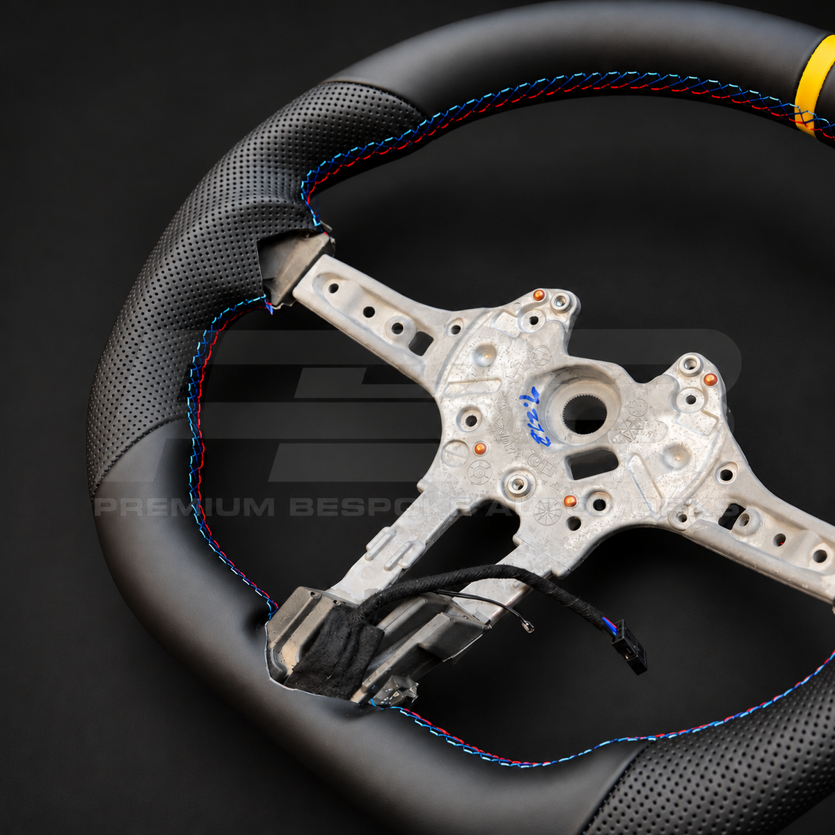 BMW M2 F87 custom steering wheel close up detail showing flat bottom, smooth black leather, black perforated leather grips, M stitching and yellow 12 o'clock marker