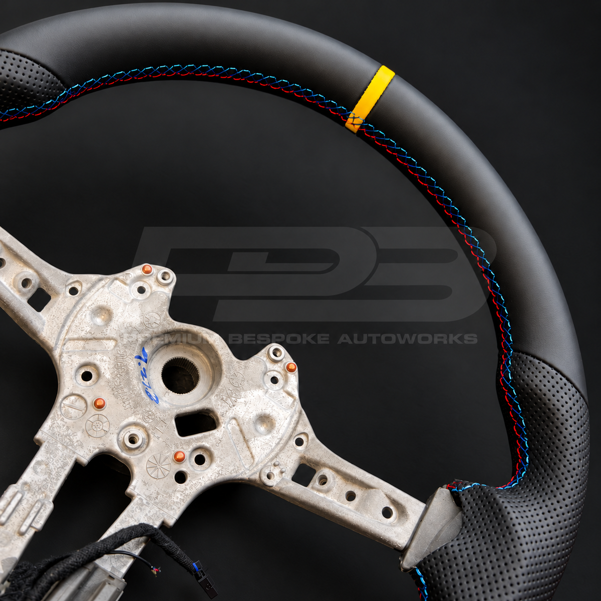BMW M2 F87 custom steering wheel close up detail showing flat bottom, smooth black leather, black perforated leather grips, M stitching and yellow 12 o'clock marker
