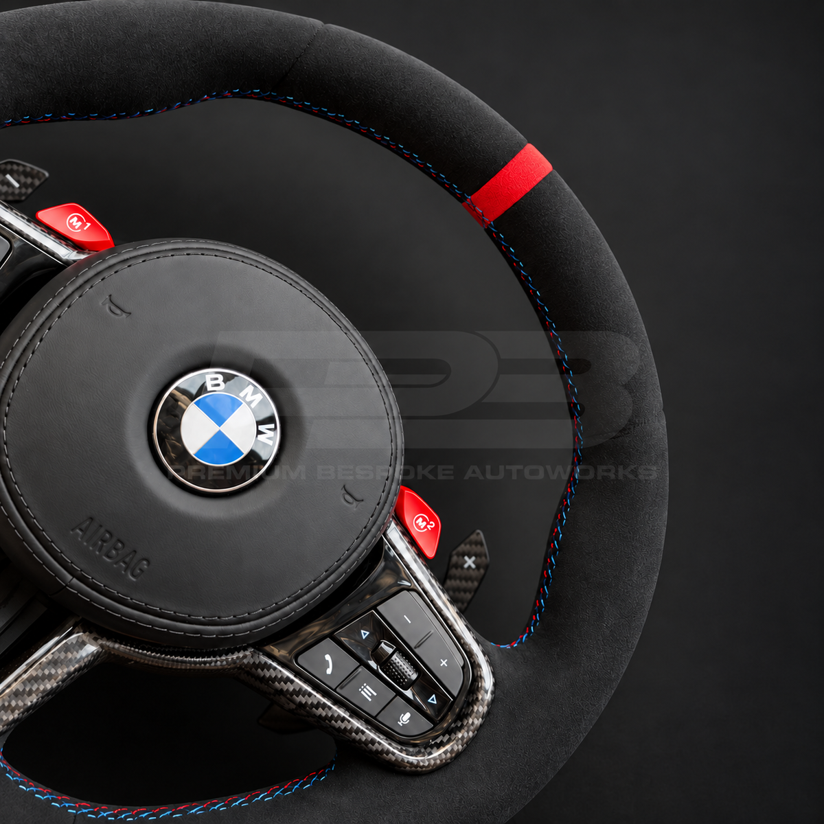 BMW M4 G82 LCI custom steering wheel close up detail showing full black Alcantara, red 12 o'clock marker, M tricolour stitching, Alcantara airbag cover, carbon trims, red M buttons