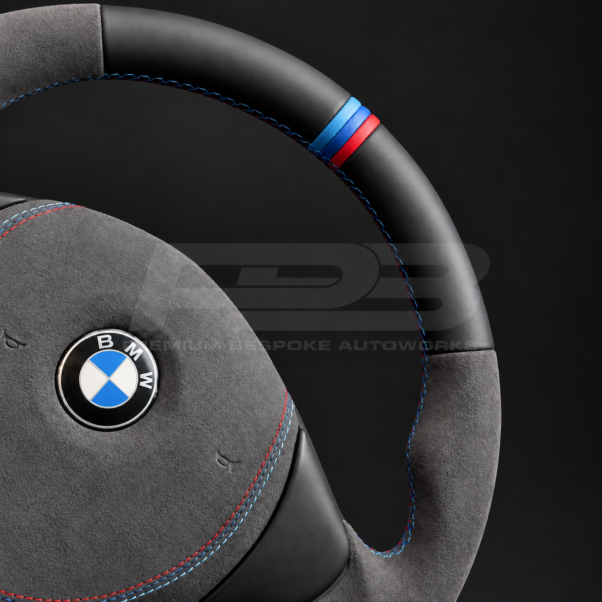 BMW Z3 custom steering wheel close up detail showing flat bottom, black leather top and bottom, dark grey Alcantara grips and airbag cover, M stitching and M stripe