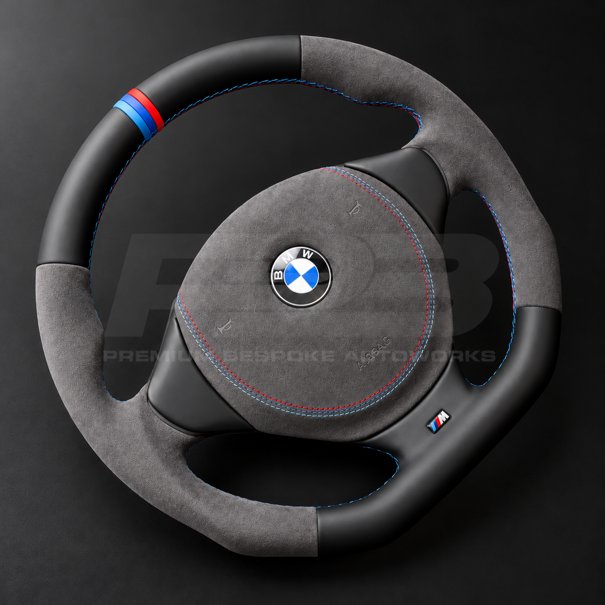 BMW Z3 custom steering wheel left angle showing flat bottom, black leather top and bottom, dark grey Alcantara grips and airbag cover, M stitching and M stripe