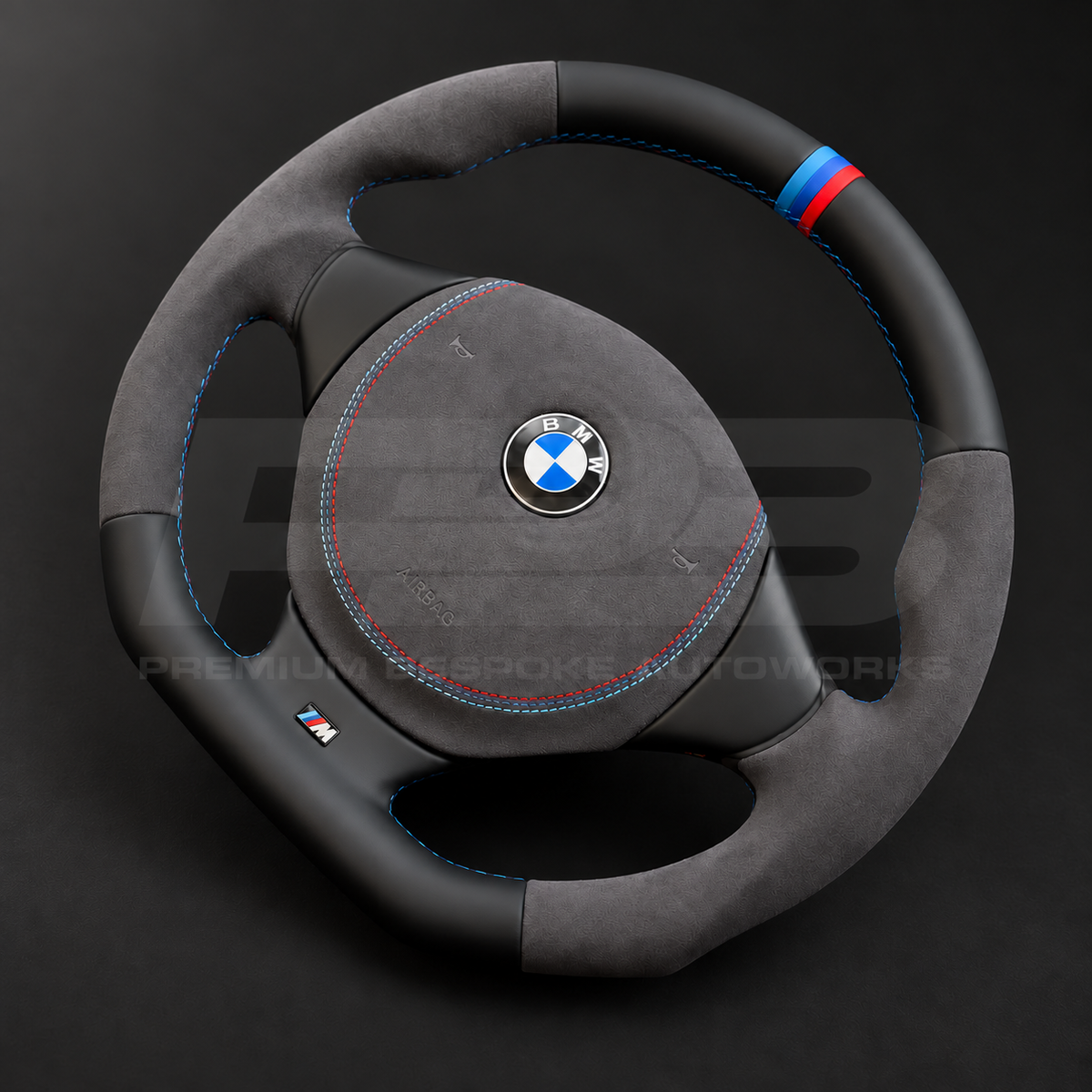 BMW Z3 custom steering wheel right angle showing flat bottom, black leather top and bottom, dark grey Alcantara grips and airbag cover, M stitching and M stripe