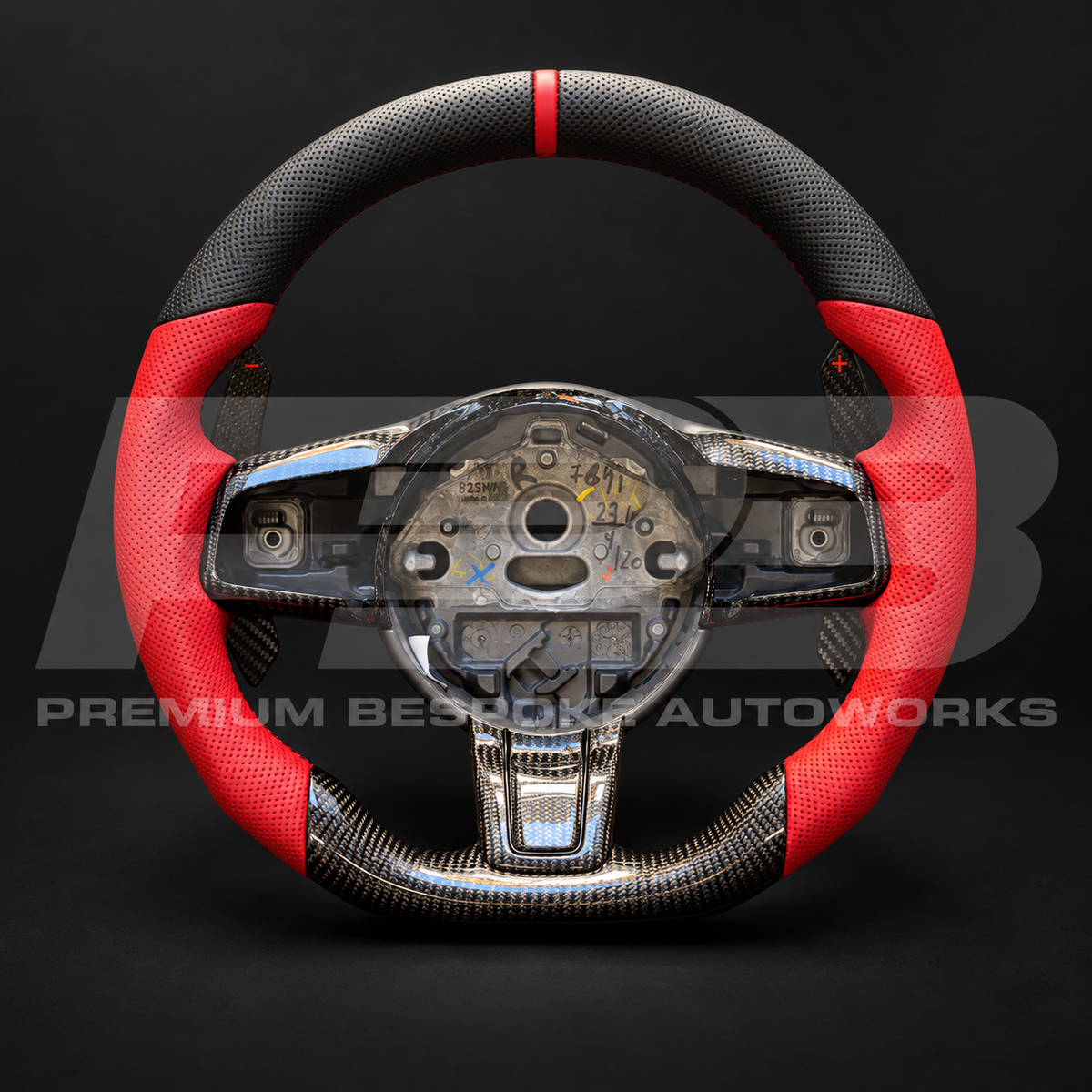 Jaguar F-Type custom steering wheel, front view: flat bottom, perforated black leather top with red 12 o'clock marker, red perforated grips, gloss carbon fibre bottom, carbon trims and carbon paddle shifters
