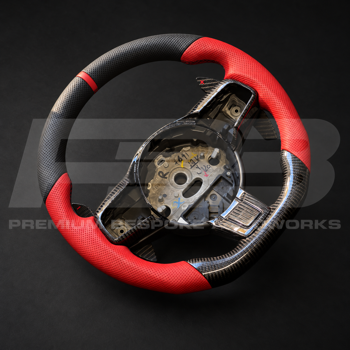 Jaguar F-Type custom steering wheel angled from above, showing the red perforated leather grips, gloss carbon fibre bottom section and carbon spoke trims
