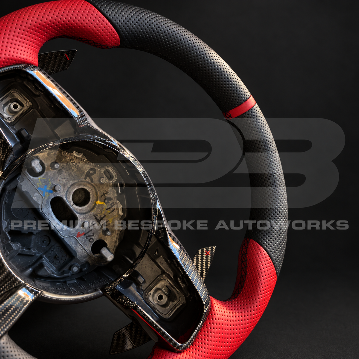 Close up of the gloss carbon fibre spoke trim, carbon paddle shifter and red perforated leather grip on a Jaguar F-Type custom steering wheel