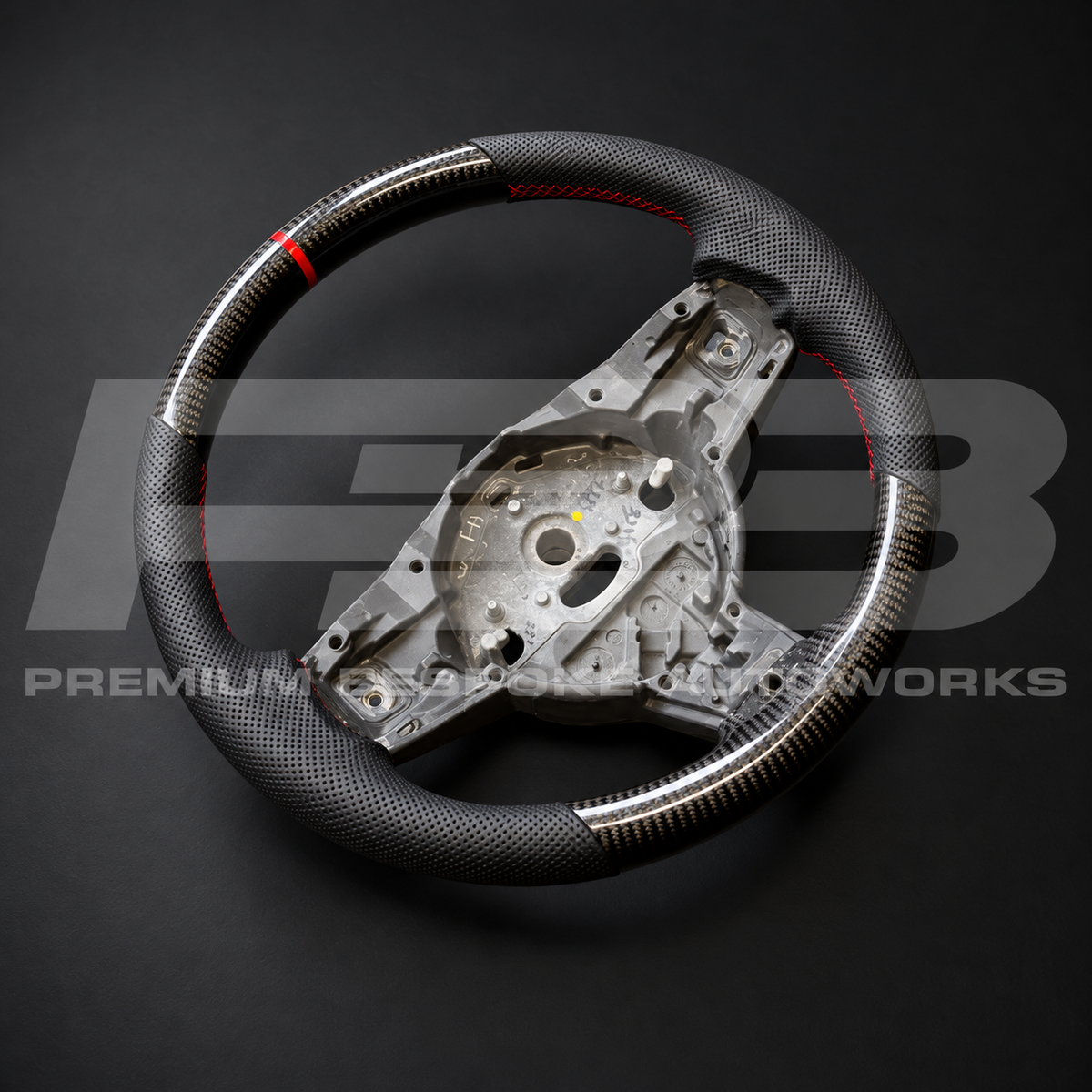 Jaguar F-Type custom steering wheel angled from the left, gloss carbon fibre with perforated leather grips and red stitching