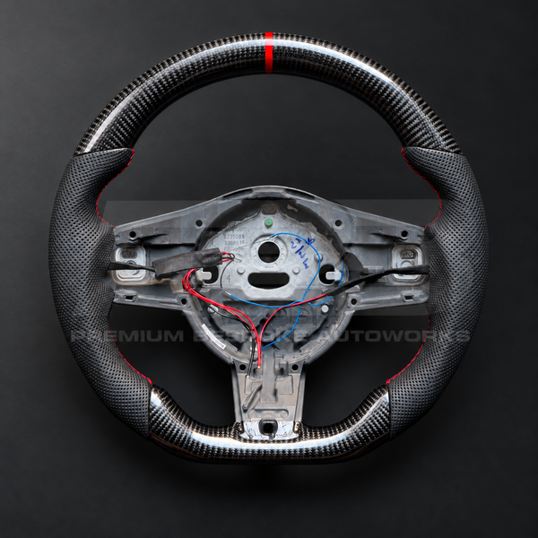 Jaguar F-Type custom steering wheel front view, flat bottom, gloss carbon fibre top and bottom, perforated black grips, red stitching and red 12 o'clock marker