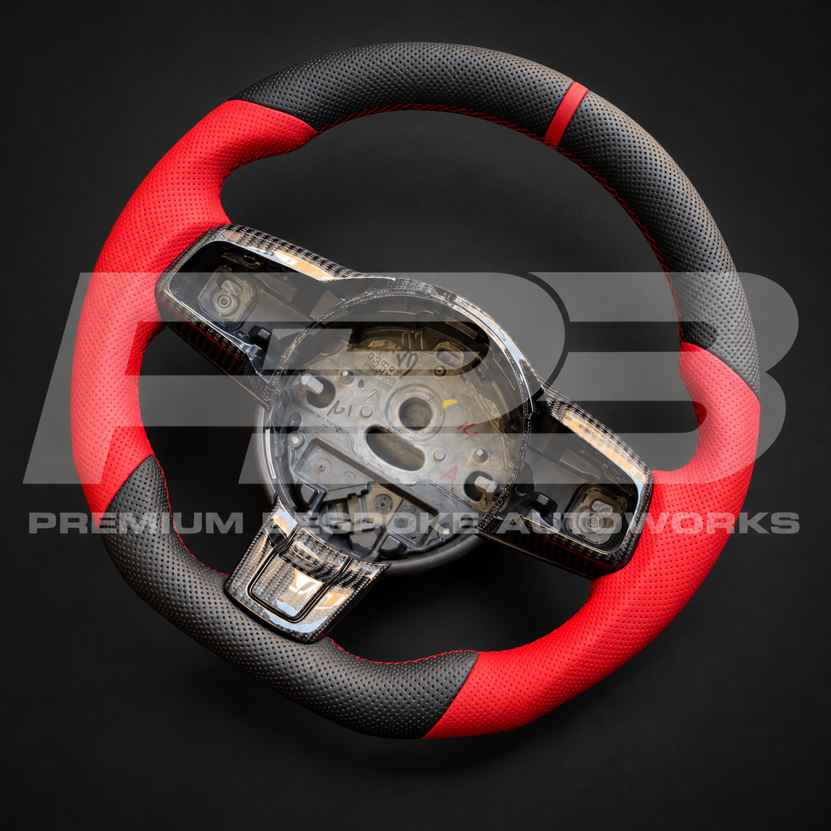 Jaguar F-Type flat bottom custom steering wheel at an angle, red perforated leather grips, black perforated leather, carbon fibre trims