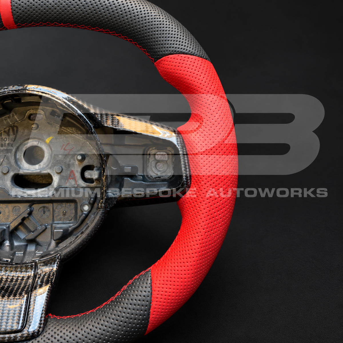 Carbon fibre lower spoke trim and red leather grip detail on a Jaguar F-Type custom steering wheel