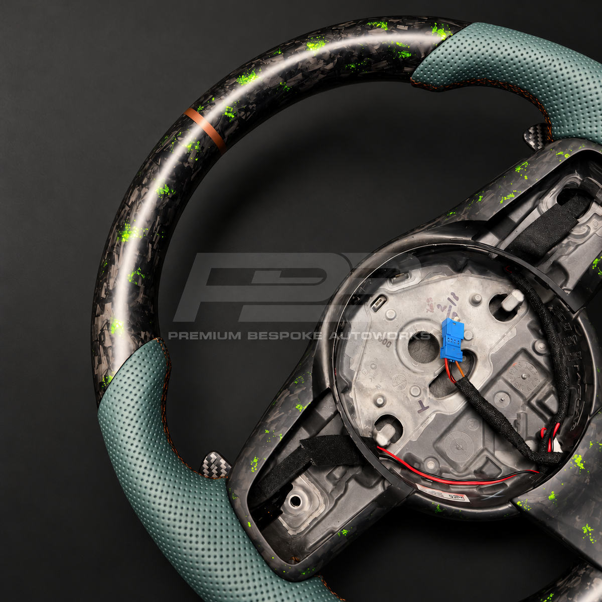 Jaguar F-Type custom steering wheel close up detail showing sports shape, green fleck forged carbon top and bottom, green perforated leather grips and bronze marker
