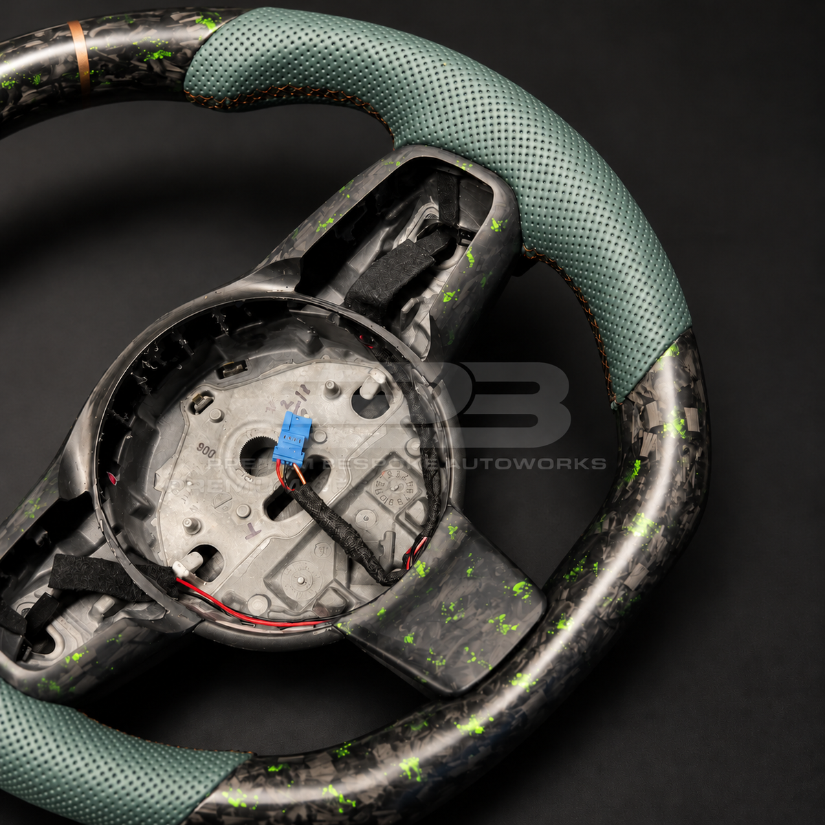 Jaguar F-Type custom steering wheel close up detail showing sports shape, green fleck forged carbon top and bottom, green perforated leather grips and bronze marker