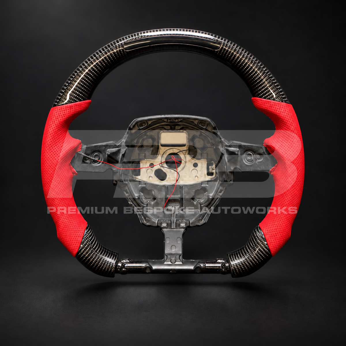 Lamborghini Huracan custom steering wheel, front view: flat top and flat bottom, gloss carbon fibre with RPM light bar in the top, red perforated leather grips and red stitching
