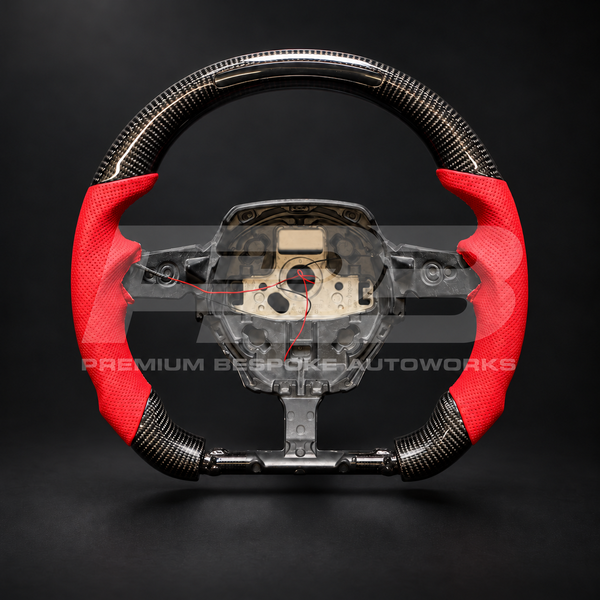 Lamborghini Huracan custom steering wheel, front view: flat top and flat bottom, gloss carbon fibre with RPM light bar in the top, red perforated leather grips and red stitching