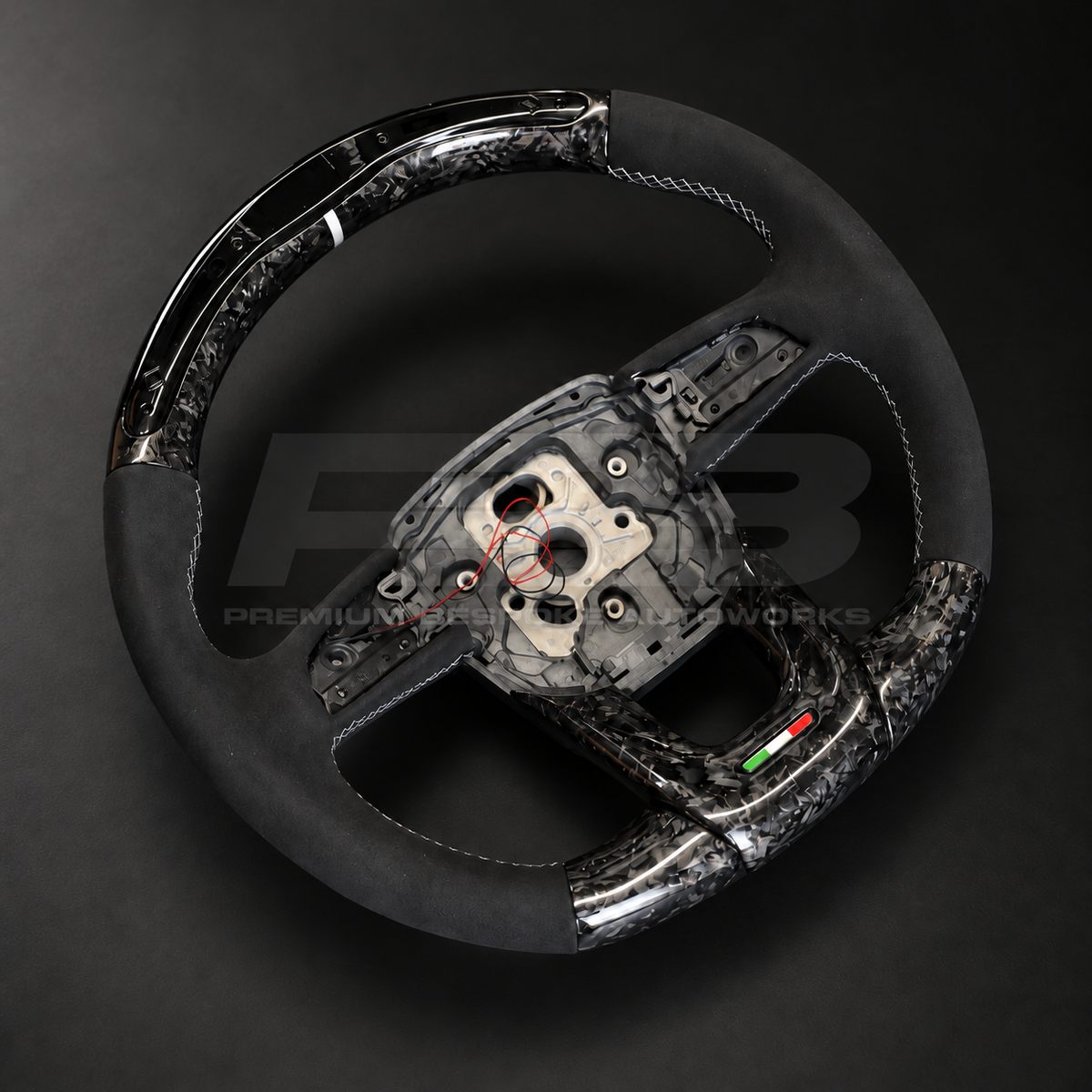 Lamborghini Urus custom steering wheel rotated to show the black Alcantara grips with silver stitching and the forged carbon top section with LED race display