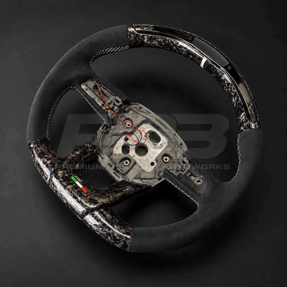 Lamborghini Urus custom steering wheel, angled view showing the marbled forged carbon weave, LED race display window and Alcantara grip